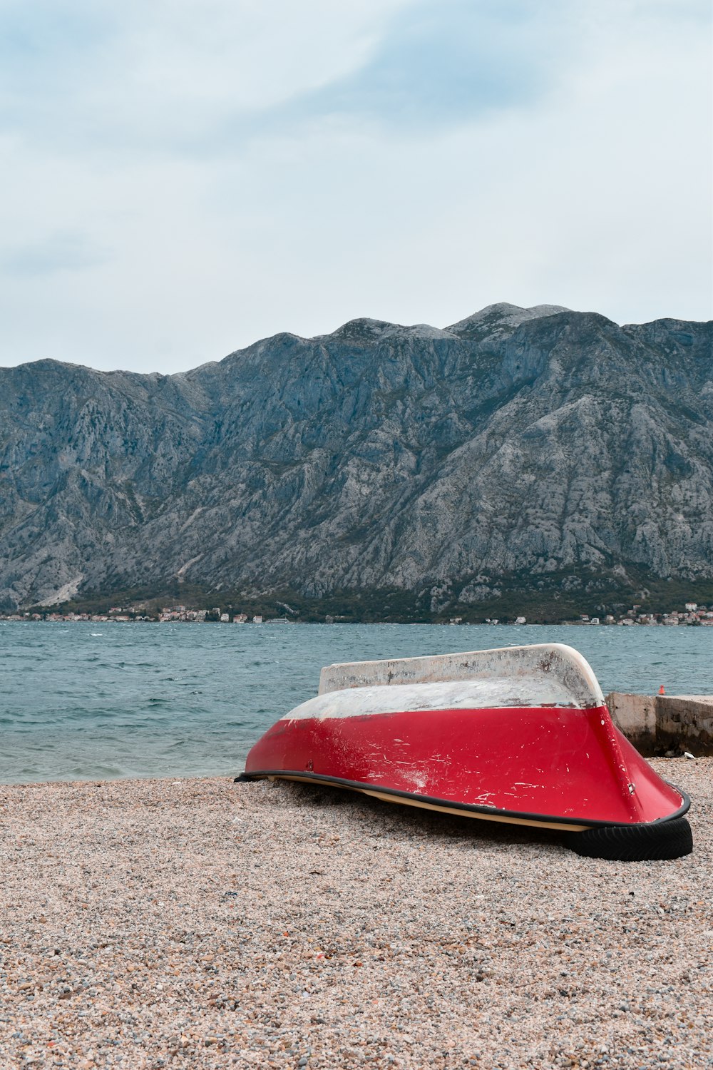 a red and white boat sitting on top of a sandy beach