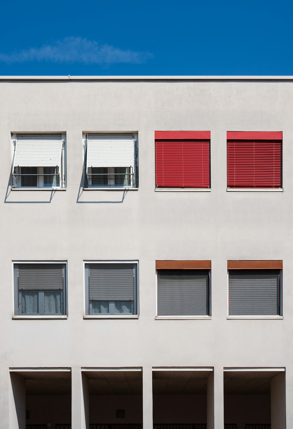 Un edificio blanco con persianas y ventanas rojas