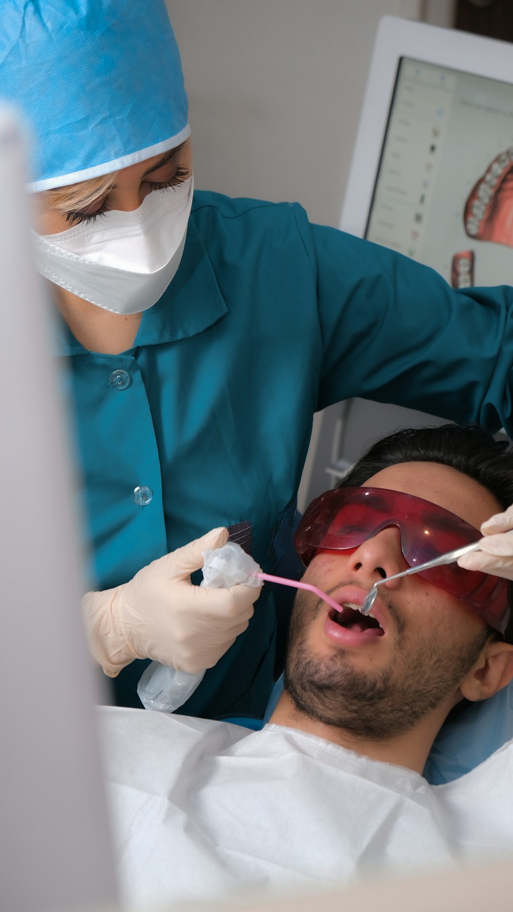 a man laying in a hospital bed while a dentist examines his teeth