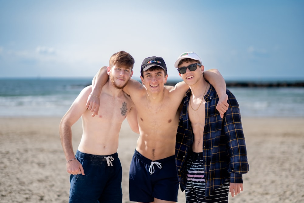 a group of three men standing next to each other on a beach