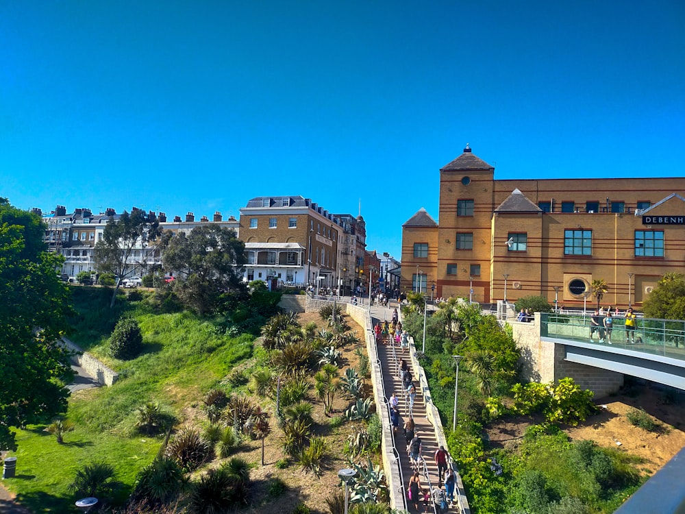 a group of people walking up a hill next to a bridge