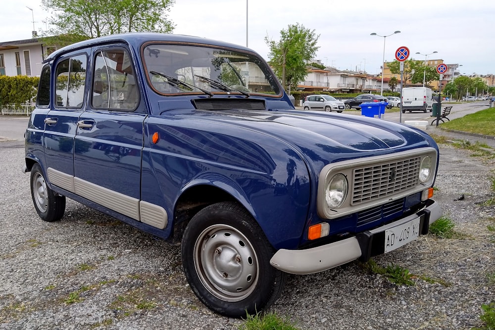 a small blue truck parked on a gravel road