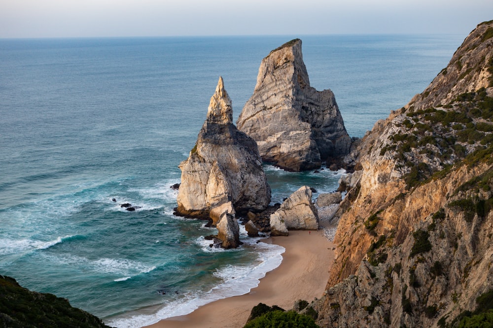 a view of a beach with two large rocks sticking out of the water