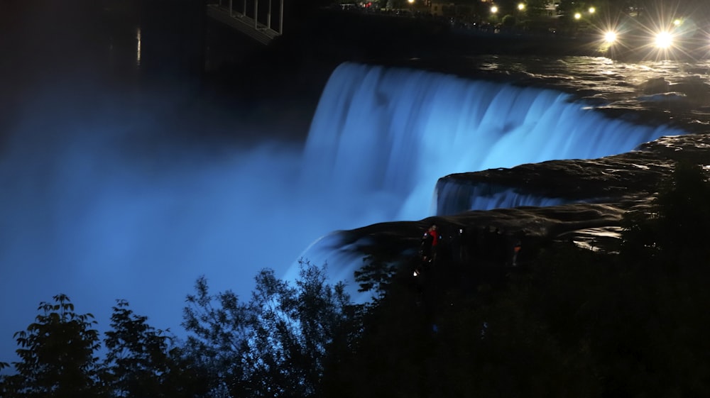 a large waterfall lit up at night with street lights