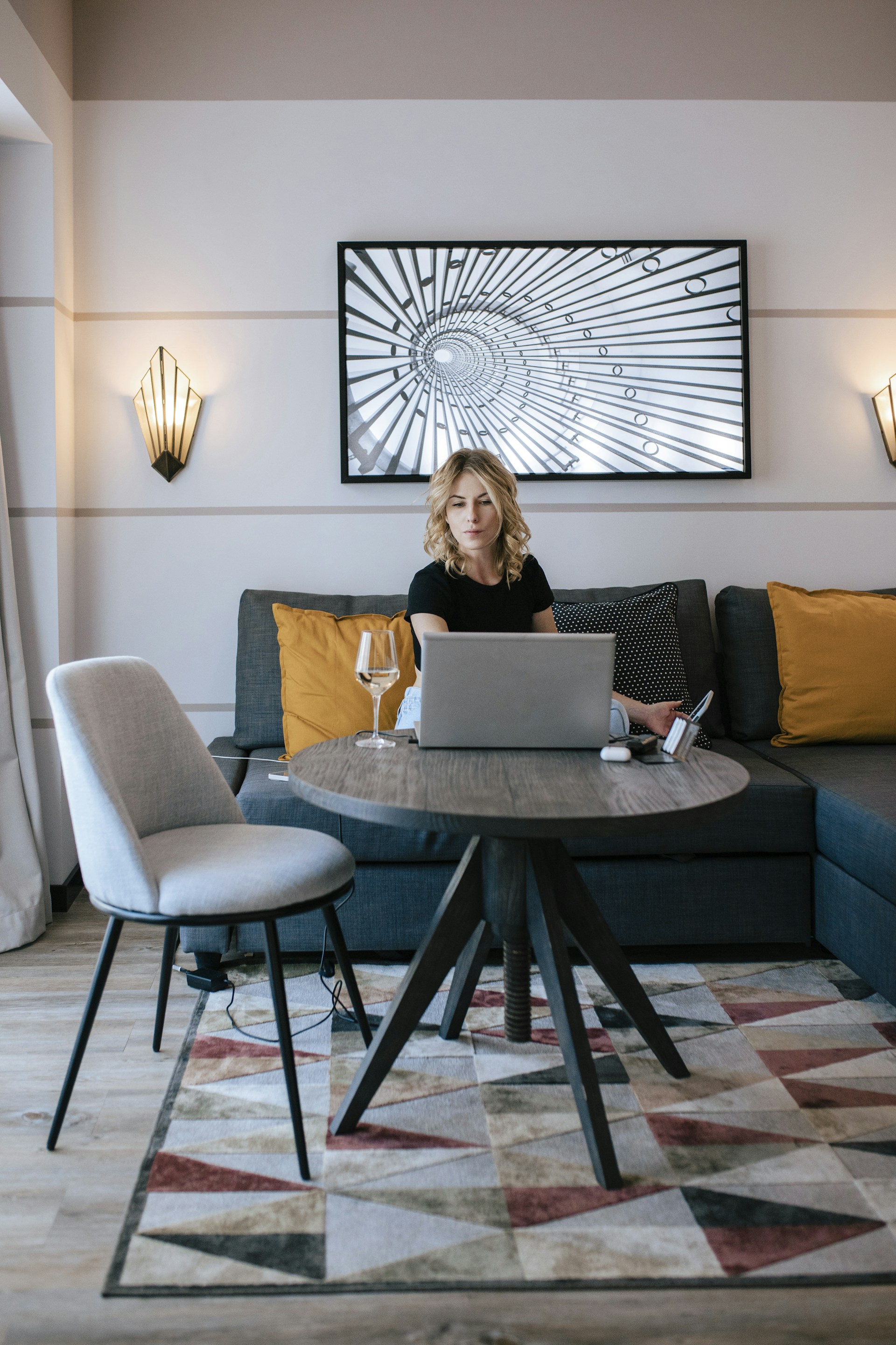 A stylish woman browsing a modern online clothing store on a laptop at a cozy home desk.