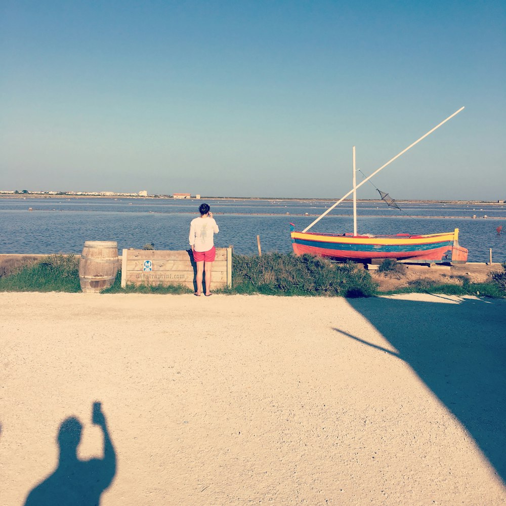 a man standing on a beach next to a boat