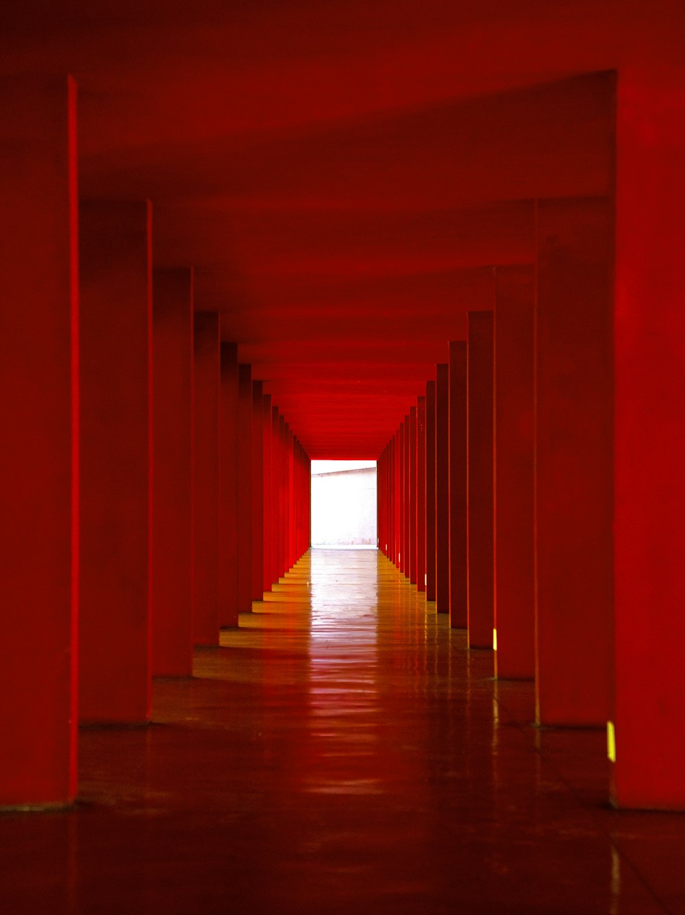 a long hallway with red walls and columns