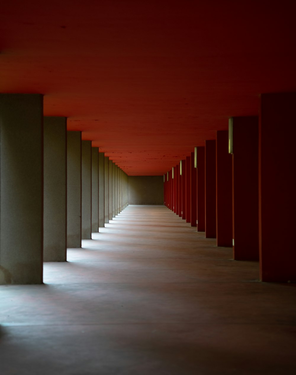 a long hallway with red walls and columns