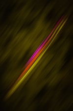 A dynamic composition featuring diagonal streaks of vibrant magenta, red, and yellow set against a dark green, blurred background. The colorful lines appear as if they are moving swiftly across the frame.