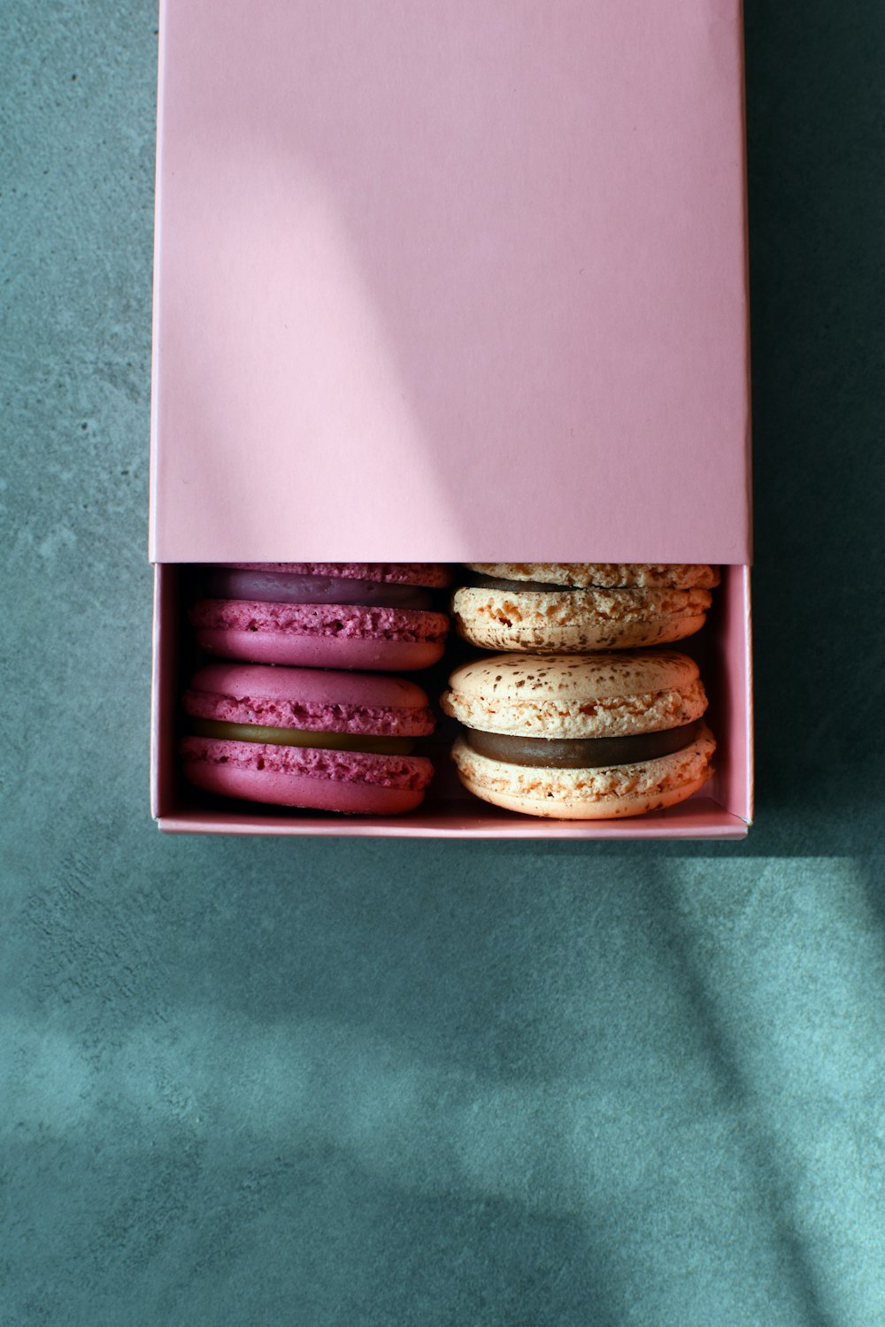 a pink box filled with macaroons on top of a table