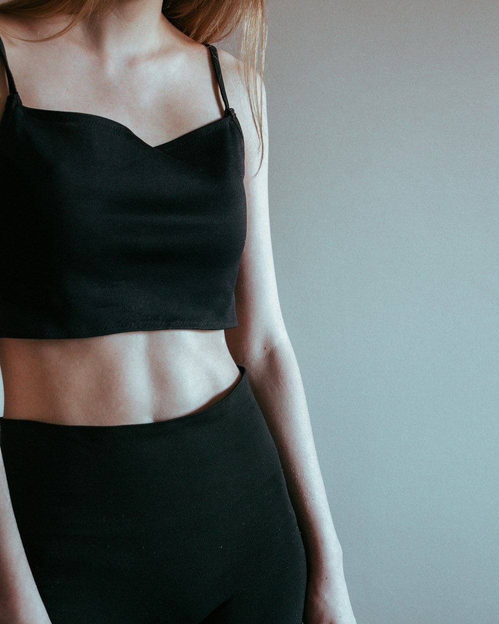 a woman wearing a black crop top and black leggings