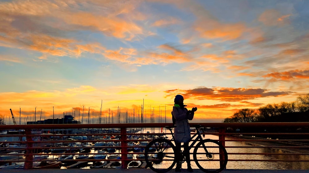 a person standing next to a bike on a bridge