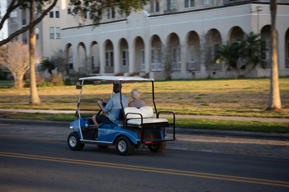 two people riding a golf cart down a street