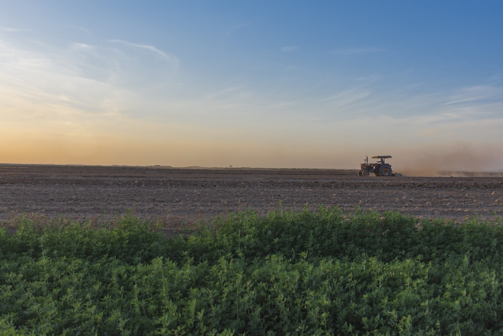 a tractor plowing a field at sunset