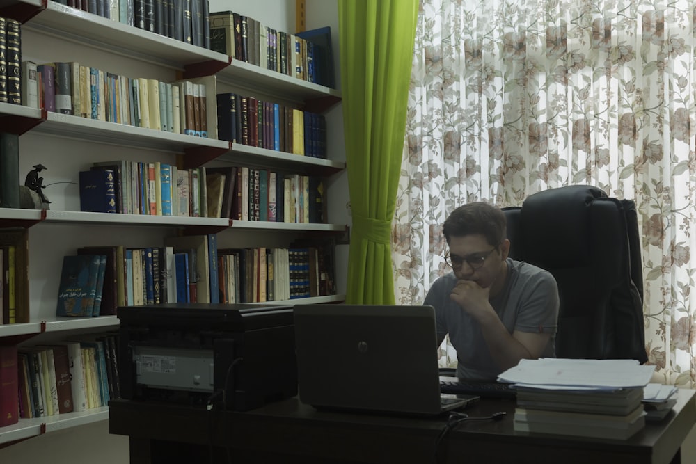 a man sitting at a desk in front of a laptop computer