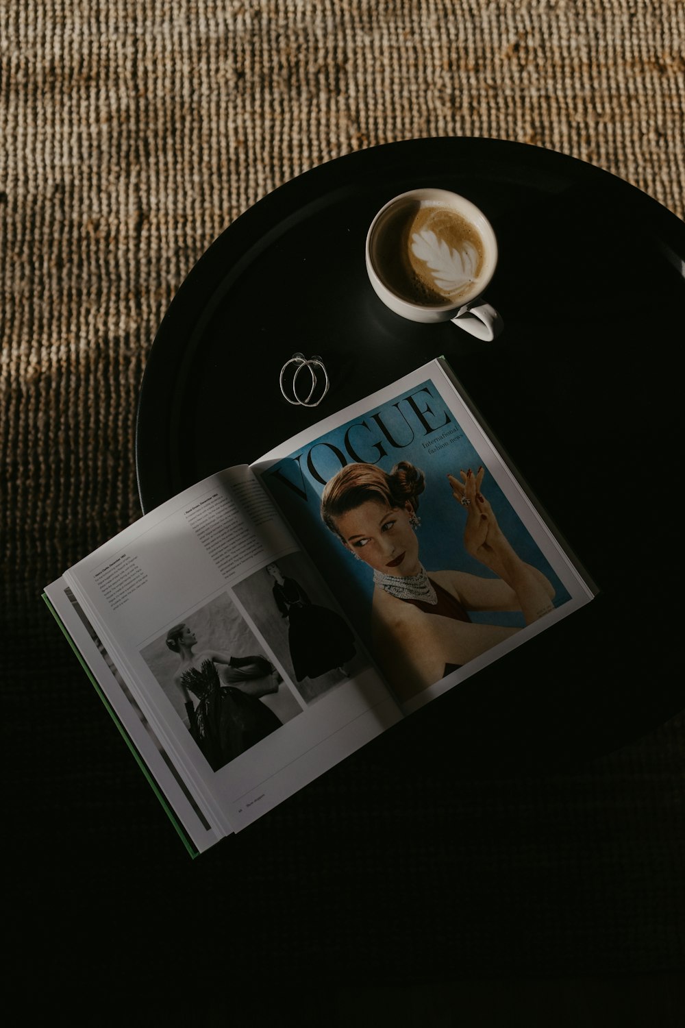 a magazine sitting on top of a black table next to a cup of coffee