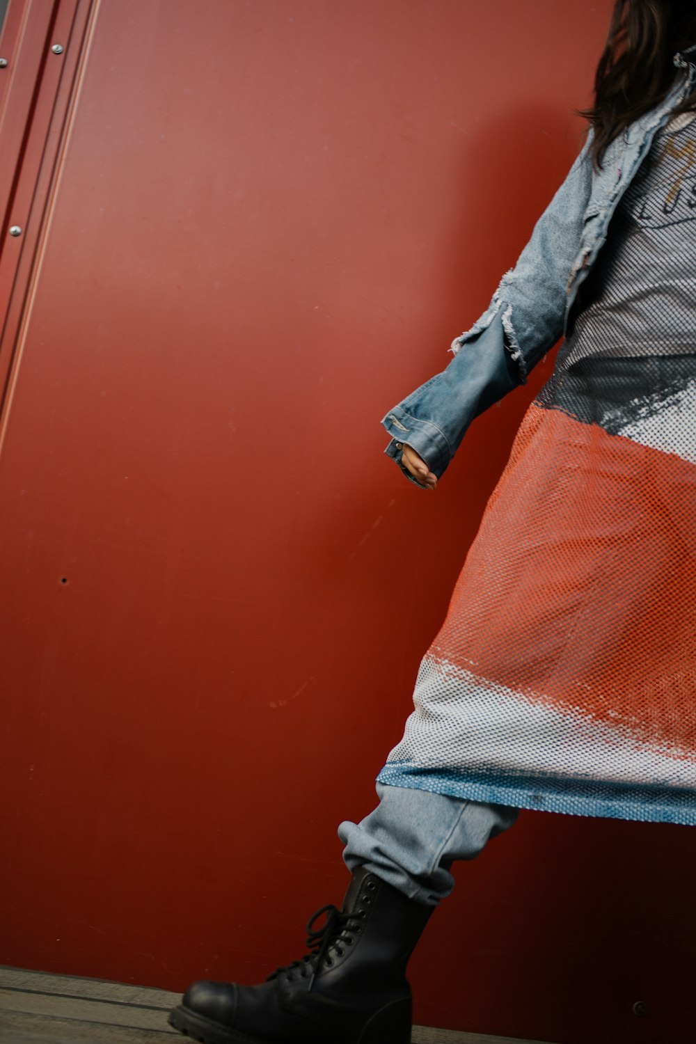 a woman standing against a red wall wearing a jean jacket