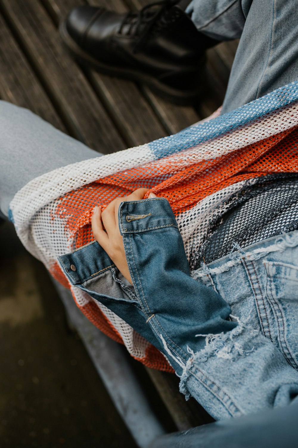 a person sitting on a bench with their hands in their pockets