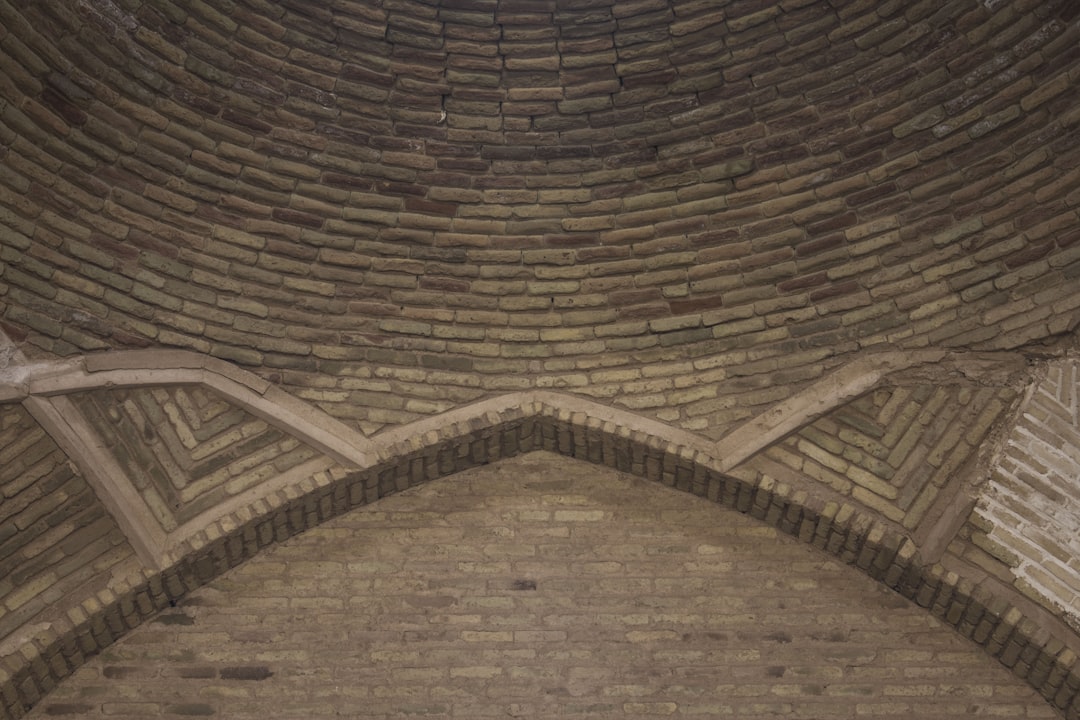 a brick building with a clock on the side of it, Deir-e Gachin Caravansarai is one of the greatest caravansarais of Iran