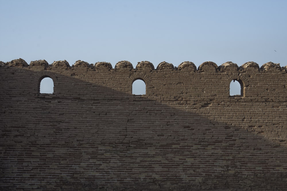 a large brick wall with three arched windows