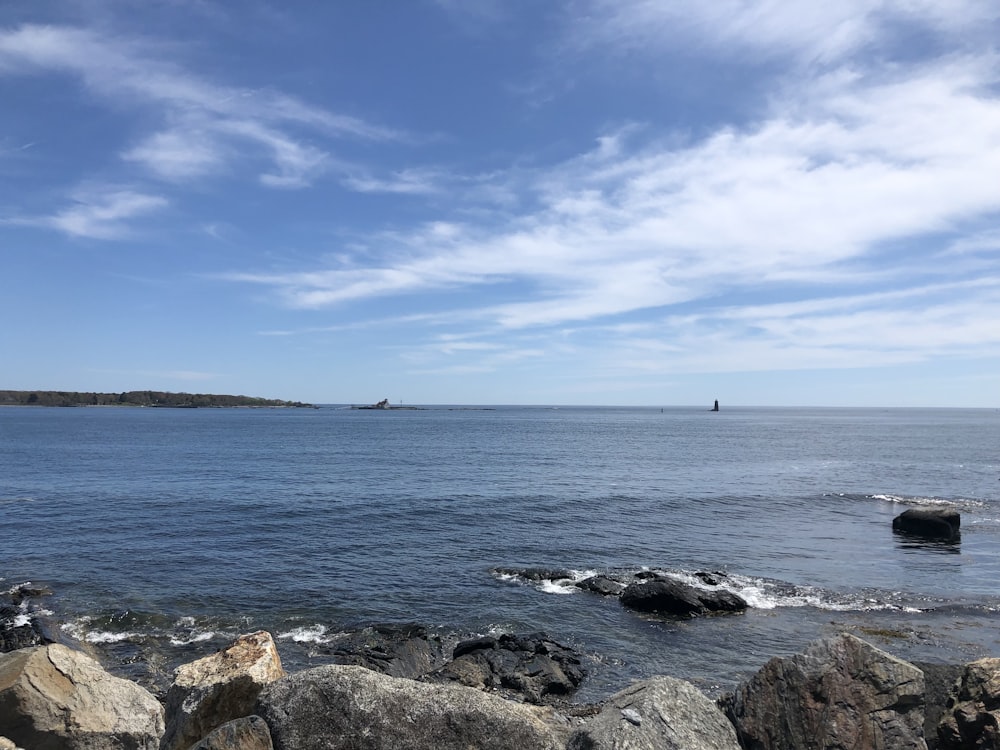 a body of water surrounded by rocks under a blue sky