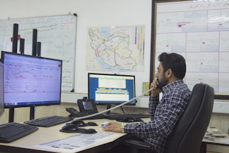 a man sitting at a desk talking on a phone