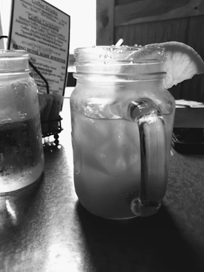 Fresh lemonade in mason jars with lemon slices and ice on a sunny day.