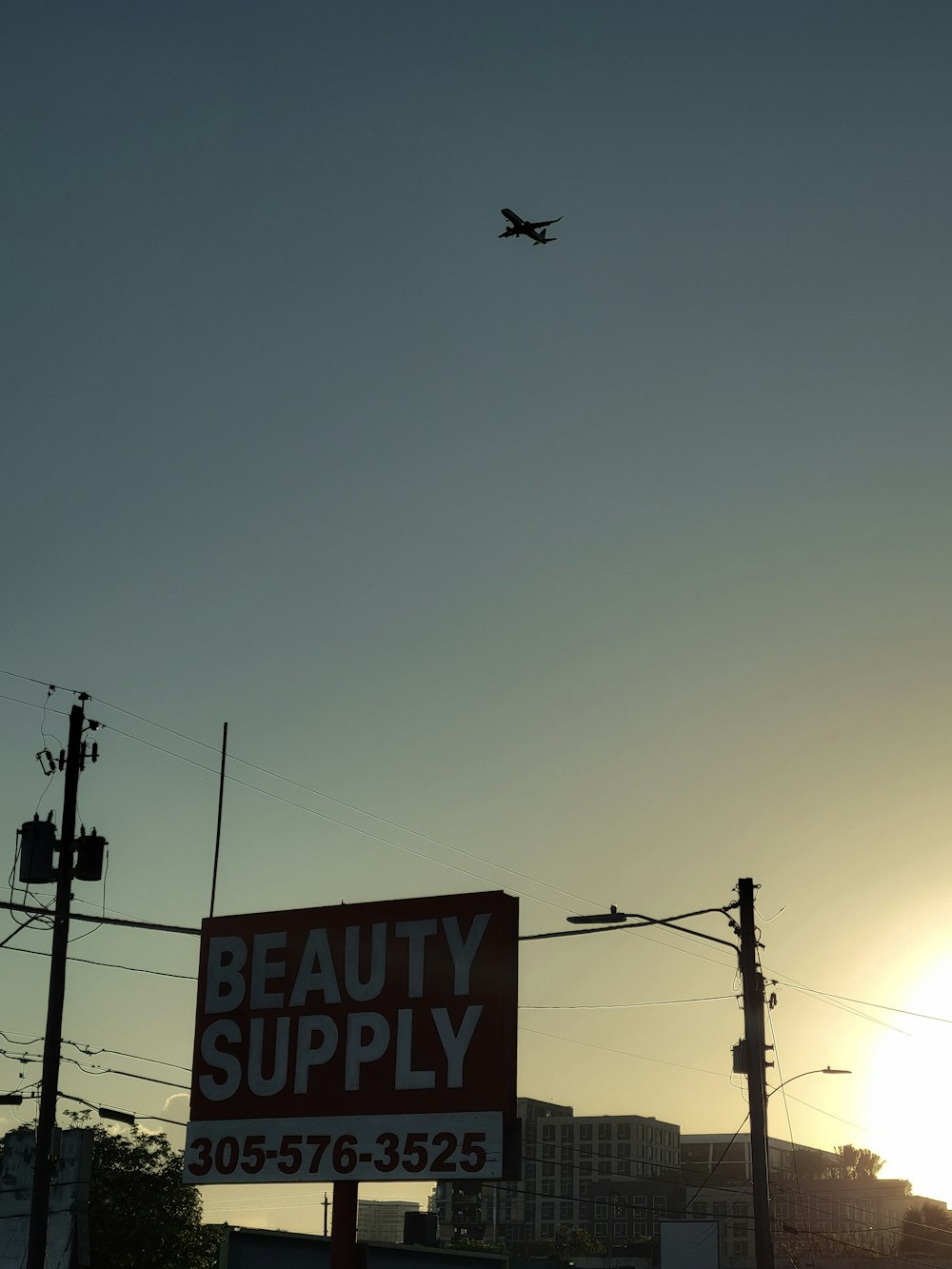 an airplane flying over a beauty supply sign