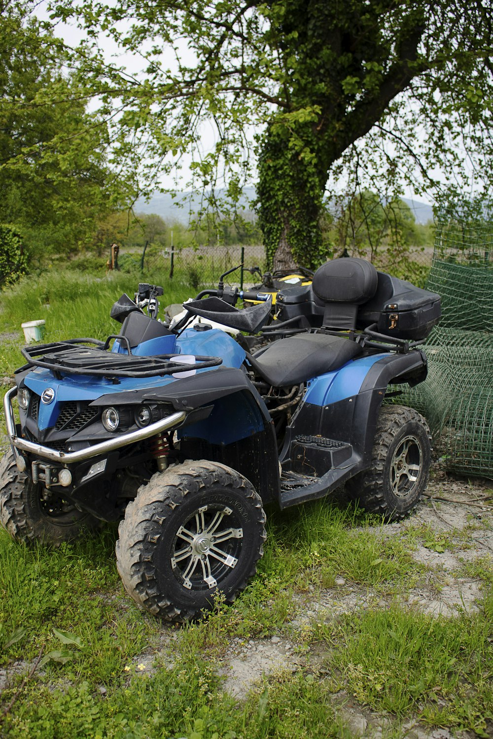 a blue and black four - wheeler parked in the grass