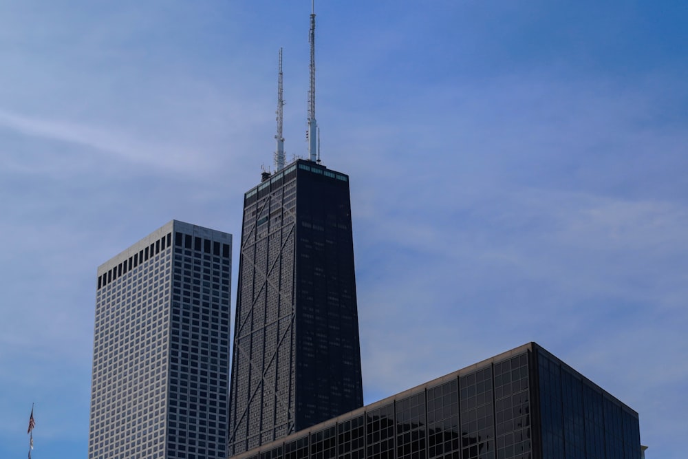 two skyscrapers against a blue sky with a few clouds