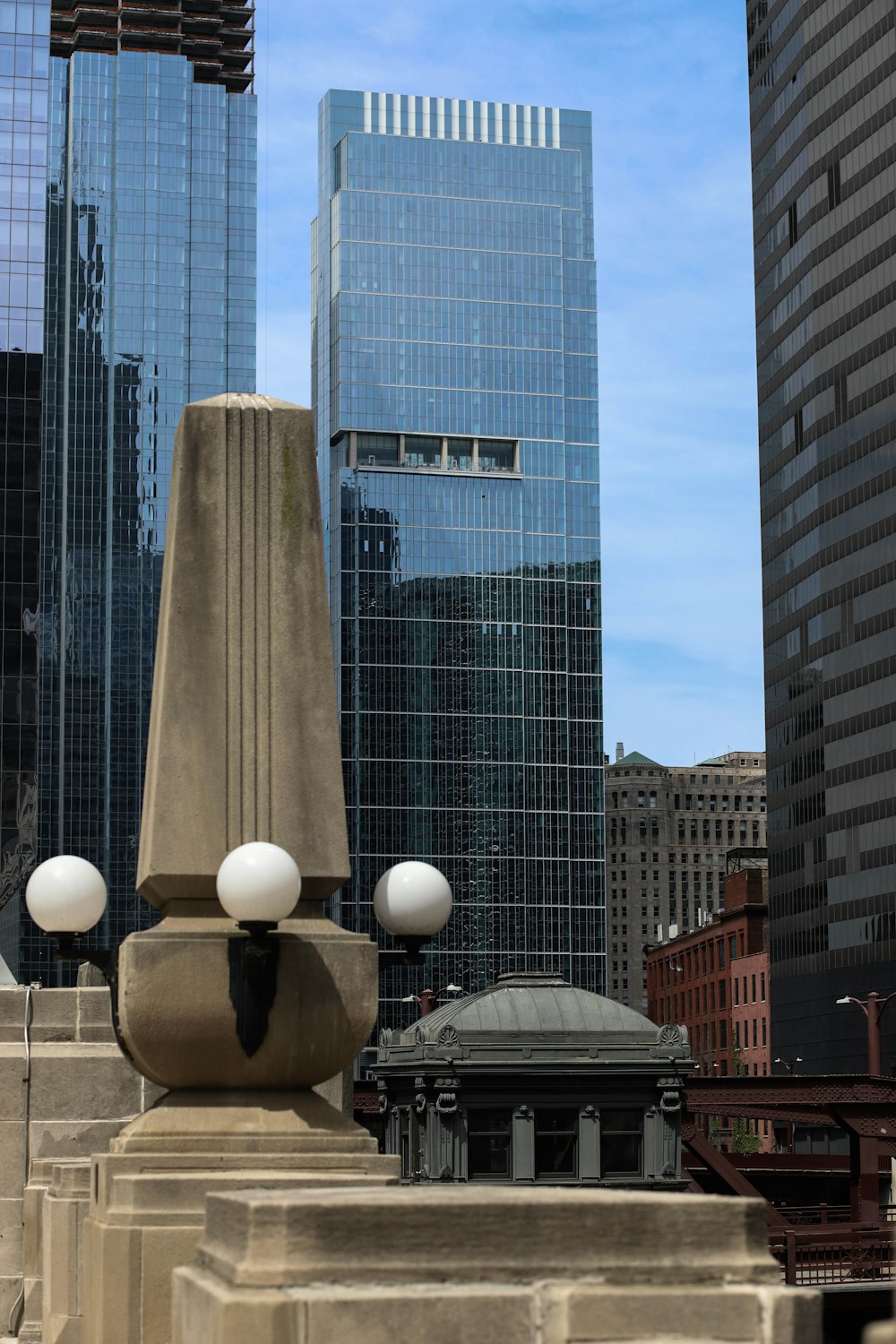 a statue in the middle of a city with skyscrapers in the background