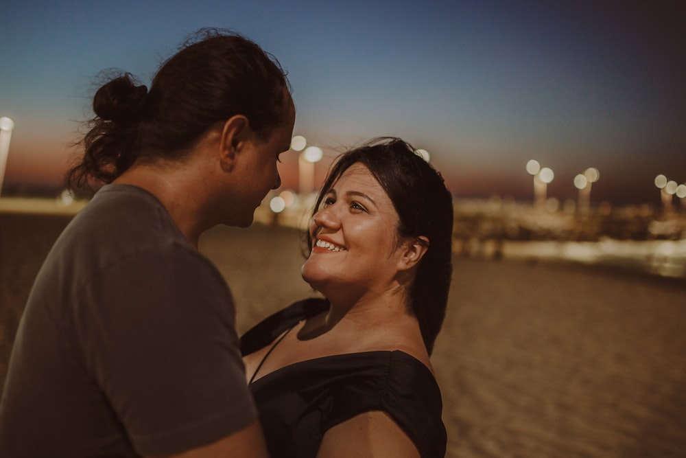 a man and a woman standing next to each other on a beach