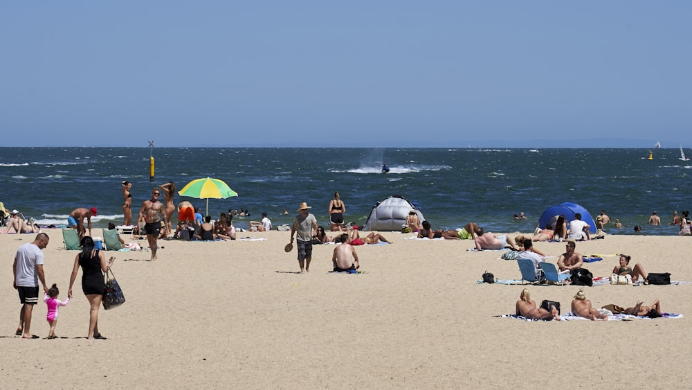 a group of people sitting on top of a sandy beach