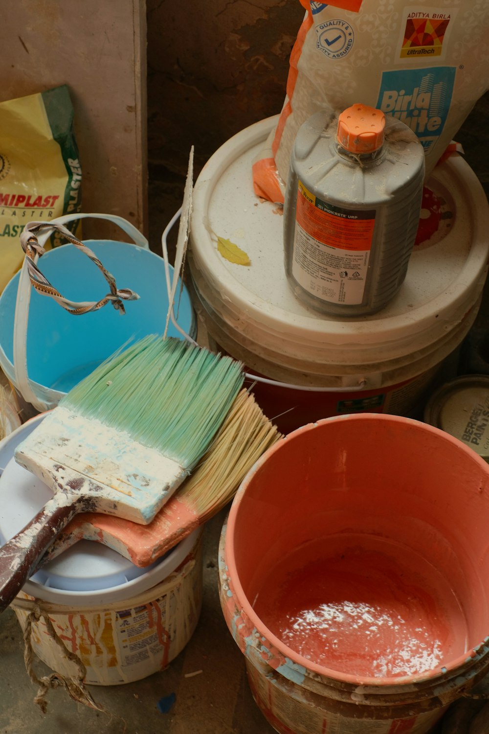 a bucket of paint next to a bucket of brushes