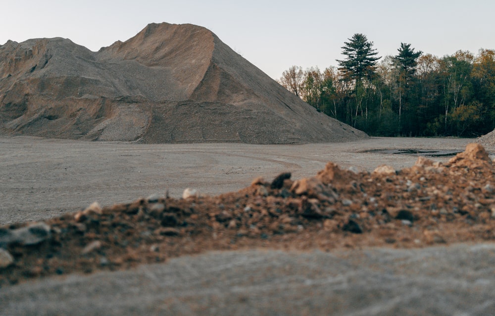 a pile of dirt sitting next to a forest