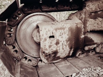 An up-close view of a large, dirt-covered metal track and wheel of heavy construction machinery. The mechanical parts are heavy-duty, showing wear and mud scattered over the surface.