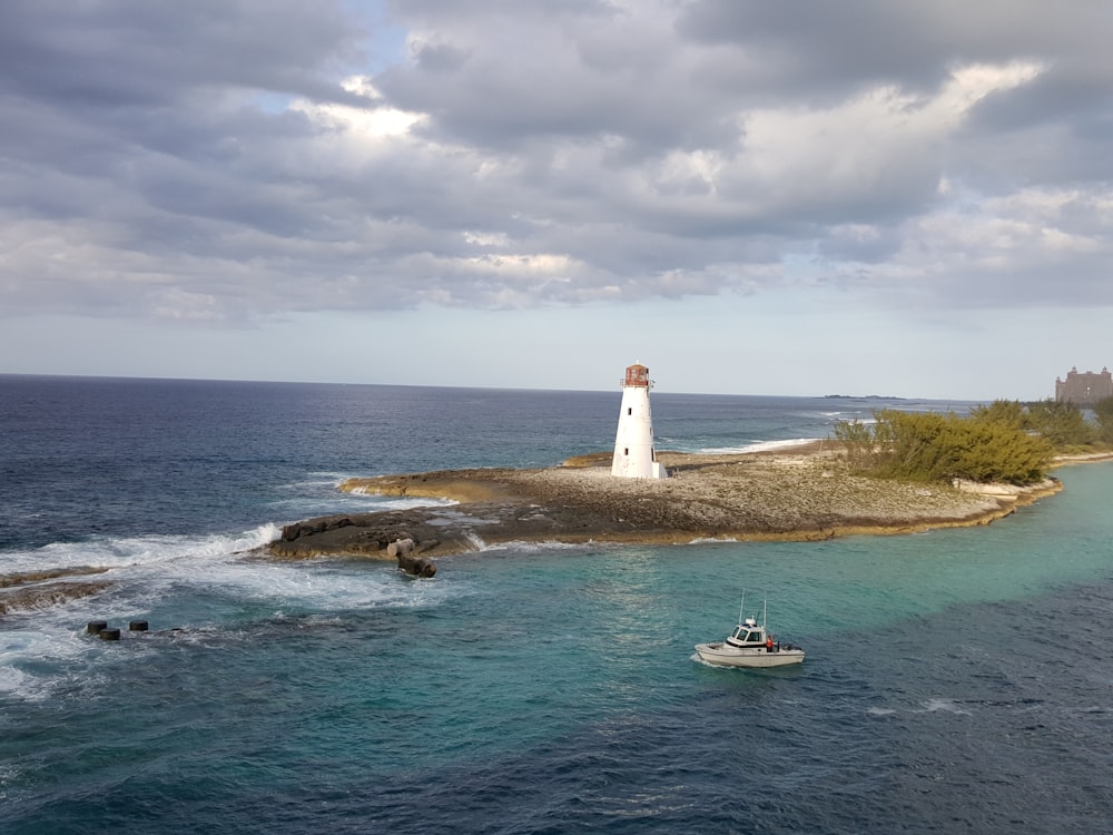 a small boat in the water near a light house