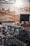 A commercial espresso machine with multiple portafilters and a row of cups on top, set against a background of a rustic, textured wall with a mix of exposed bricks and plaster.