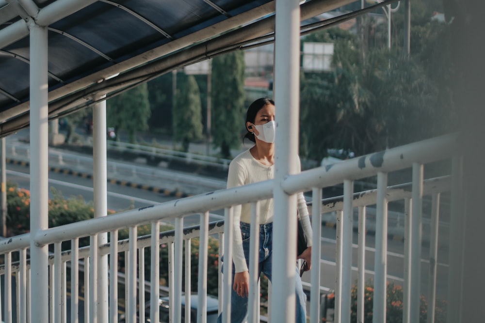a woman wearing a face mask standing on a bridge