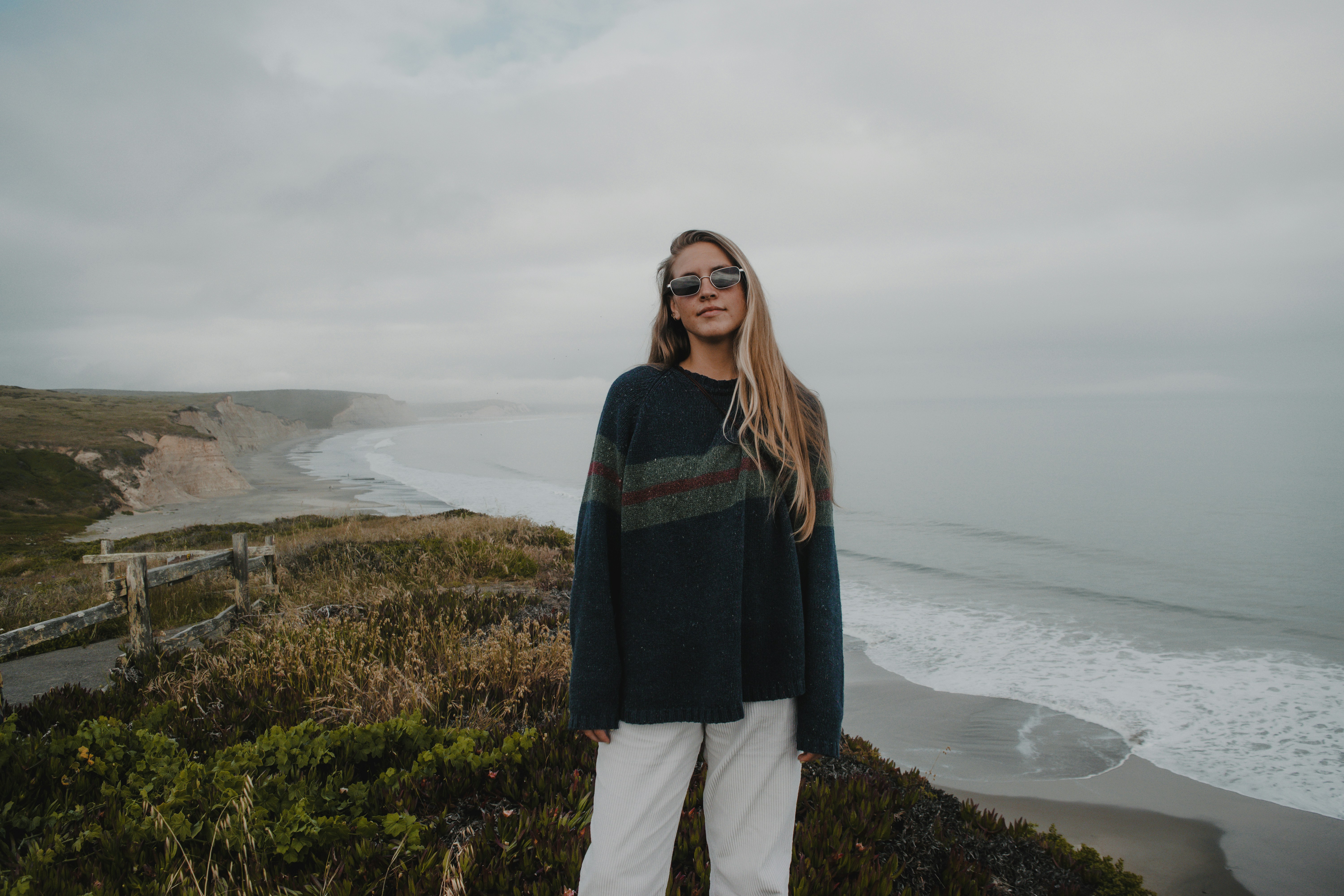 a woman standing on top of a hill next to the ocean
