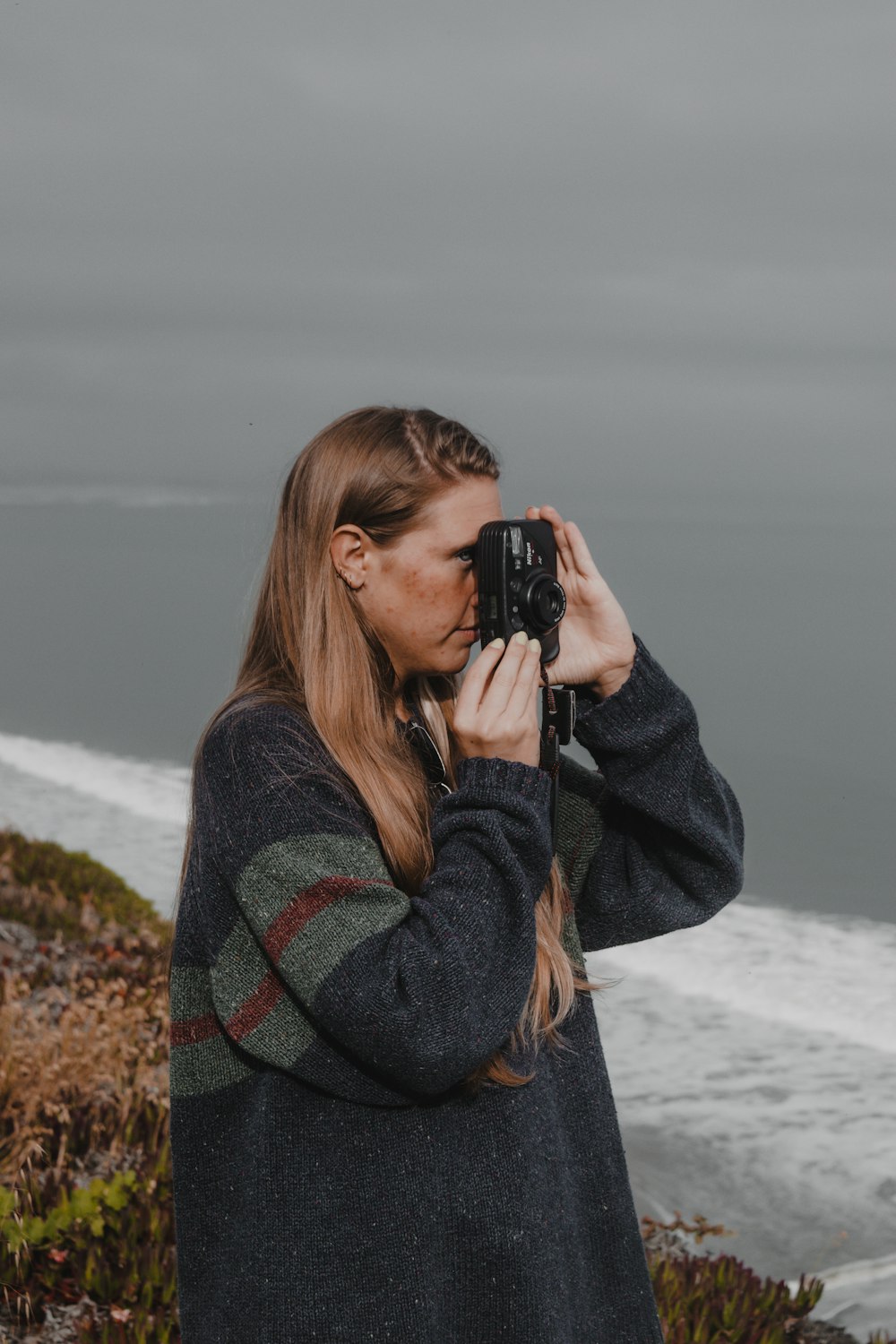 a woman taking a picture of the ocean with a camera