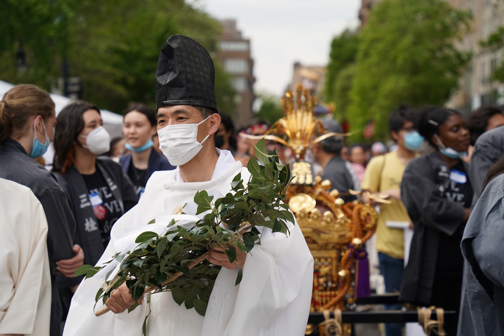 a man wearing a face mask and holding a bunch of greenery