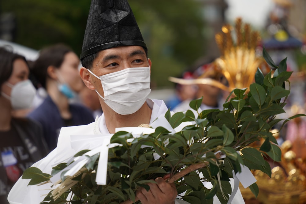 a man wearing a face mask and holding a plant