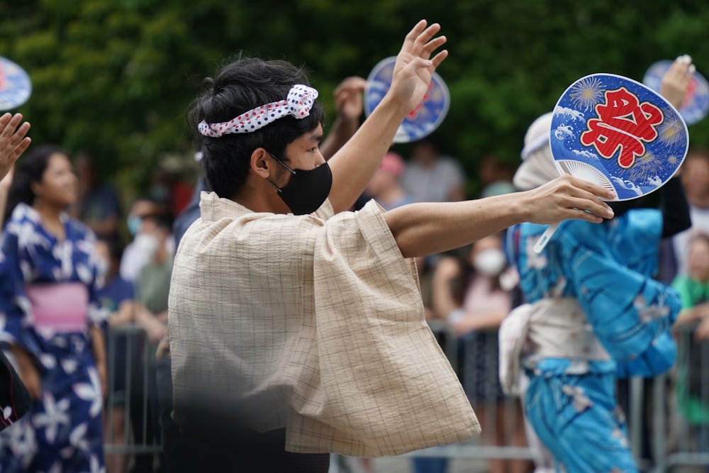 a woman in a kimono holding a fan in front of a crowd