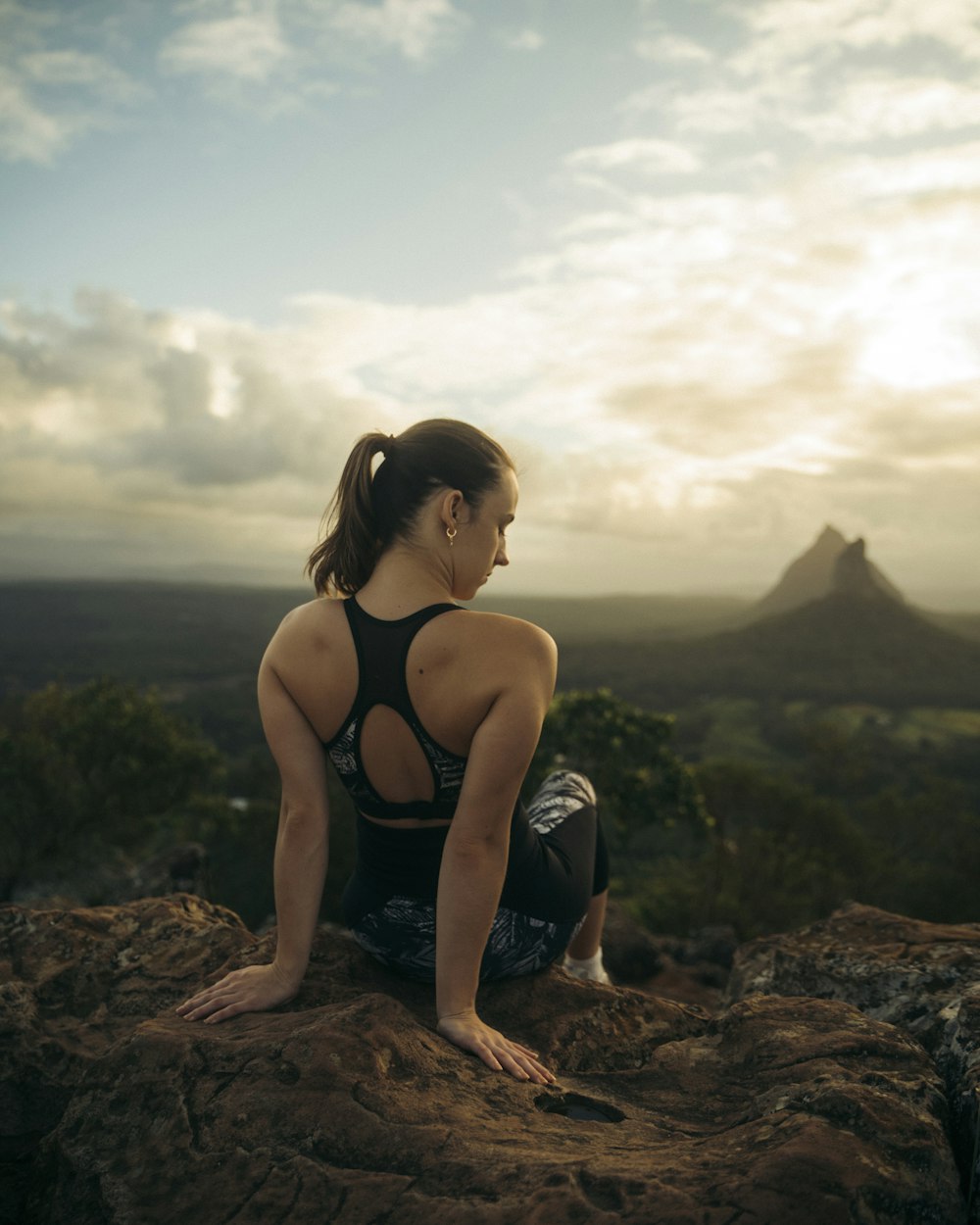 a woman sitting on top of a large rock