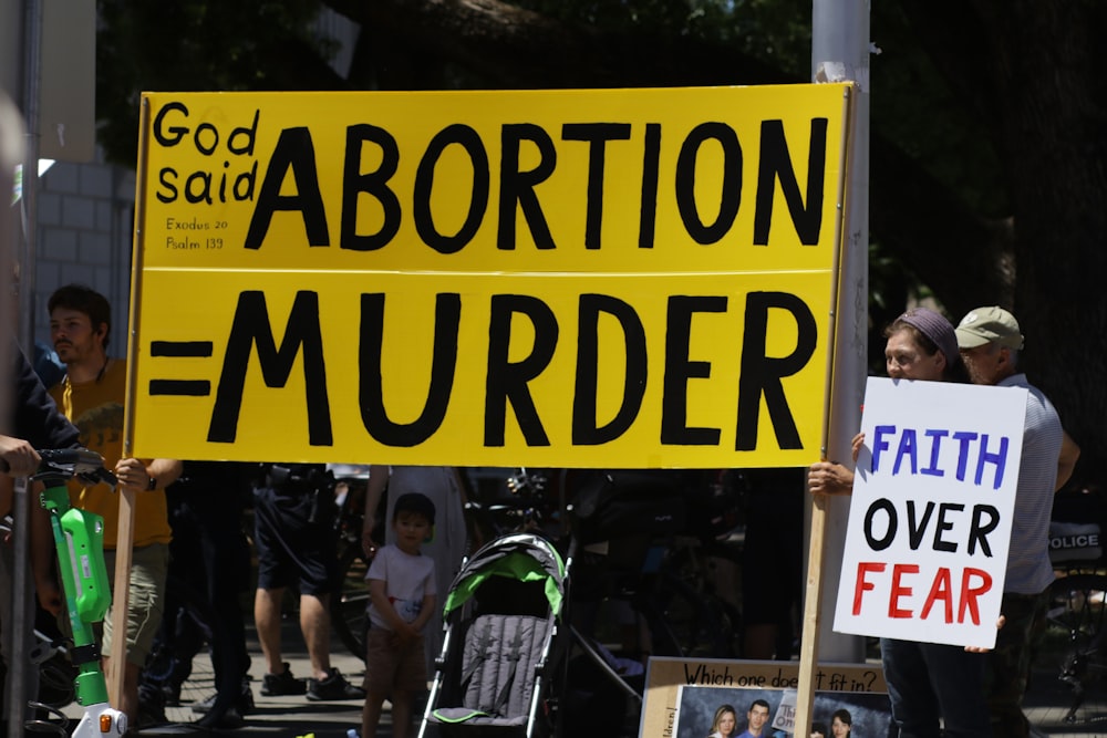a group of people holding a sign that says, god said abortion =