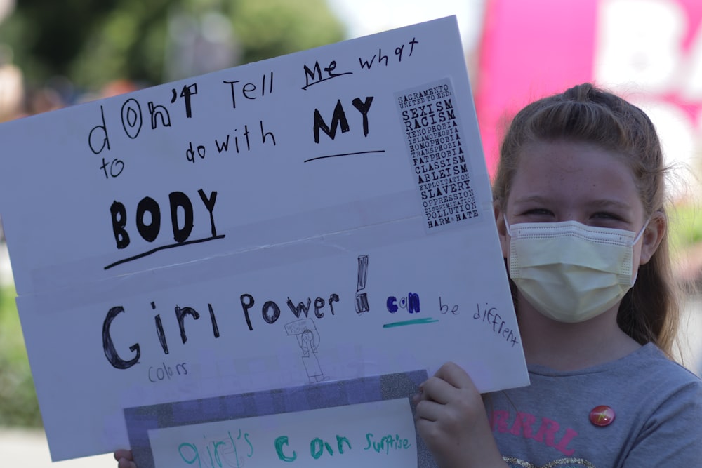 Una niña sosteniendo un cartel que dice No me digas qué hacer