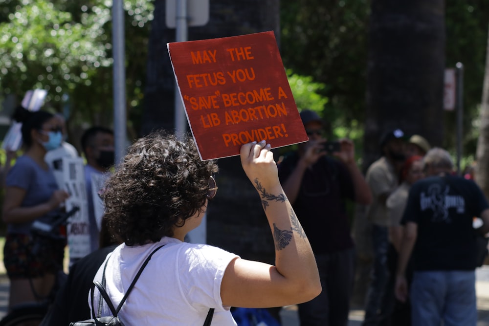 a man holding up a sign that says may the fetus be before a hair
