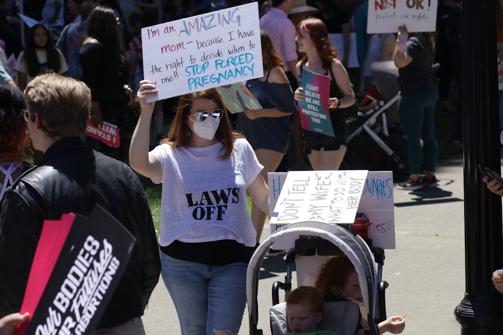 a group of people walking down a street holding signs