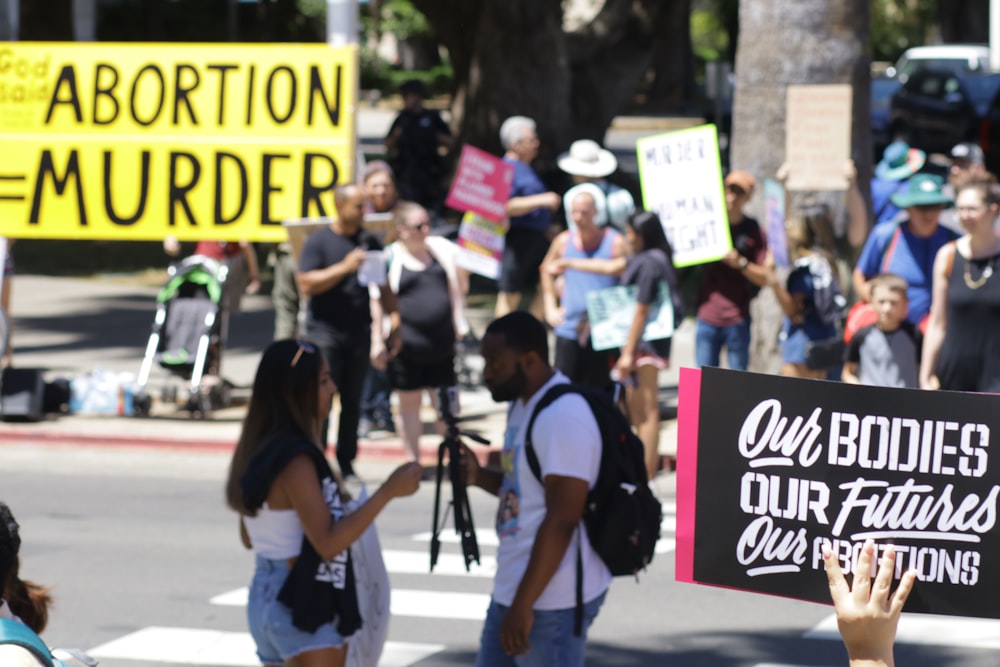 a group of people walking down a street holding signs